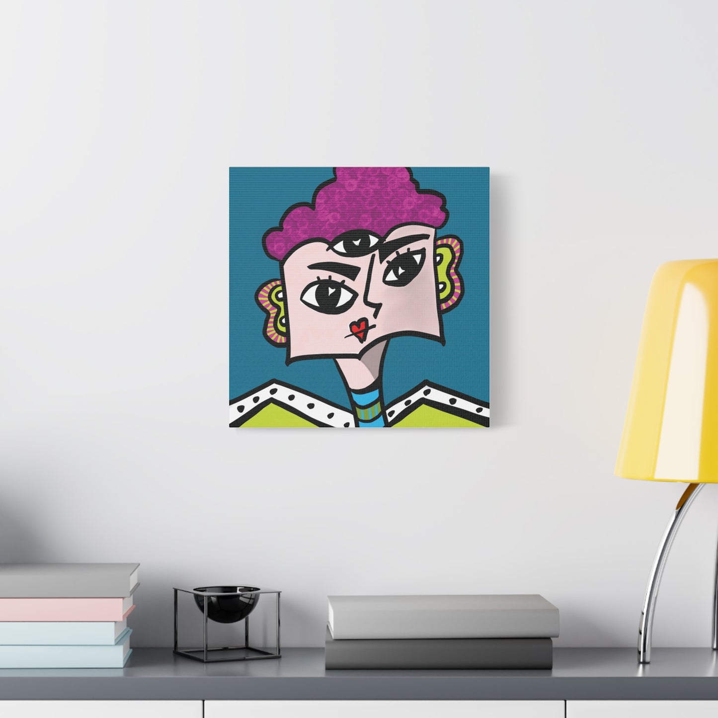 Colorful abstract art piece on a wall above a desk with books and a lamp.