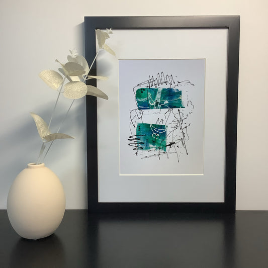 Image featuring a framed artwork positioned on a shelf with a ceramic vase and foliage.  The artwork, created by Julia Hargreaves, features free-form patterns and dynamic lines in shades of blue-green and black,