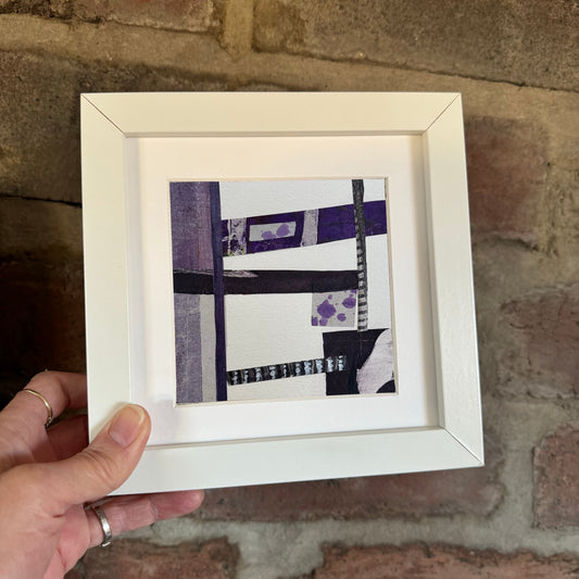 Image featuring a small abstract artwork being placed against a red brick wall.
