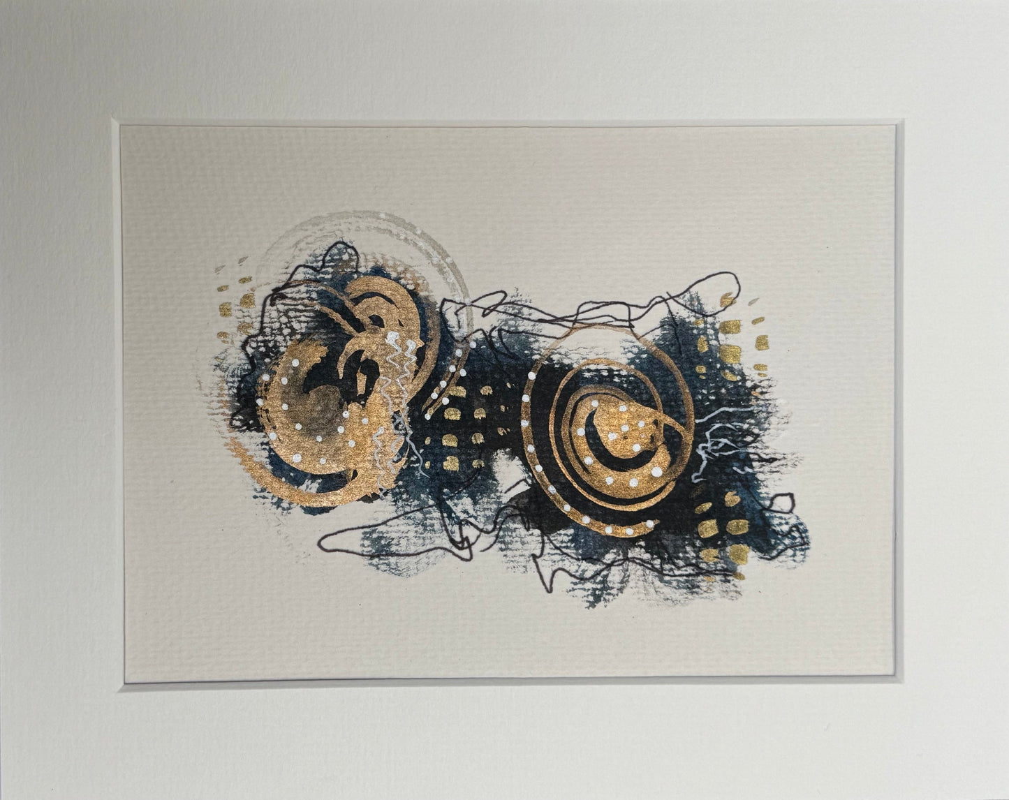 Image of an abstract, matted, original mixed media painting that showcases structured patterns and fluid brush strokes in blue, gold, and black hues.