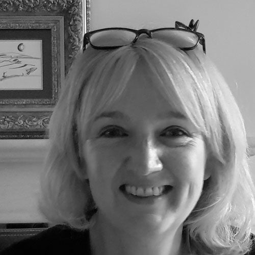 Black and white photograph of artist Julia Hargreaves.  The image shows the artist smiling, a pair of spectacles on top of her head